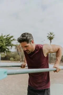 A concentrated man training, doing dips during a workout, vertical photo wi.. Stock Photos