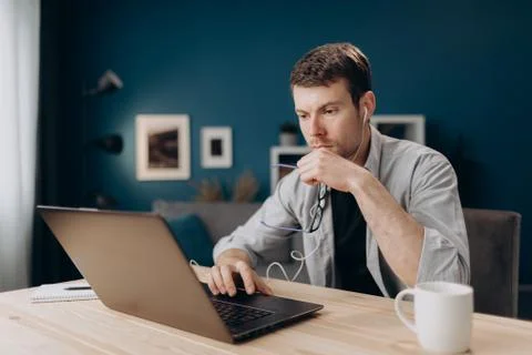 Concentrated man using laptop for remote work at home Stock Photos