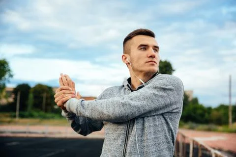 Concentrated man while stretching at the stadium Stock Photos