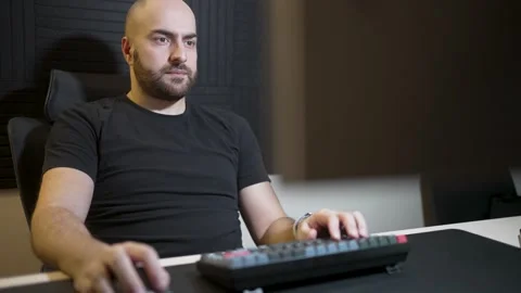 Concentrated Man Working on a Computer in a Modern Studio. A bearded man in.. Stock Footage 303012795