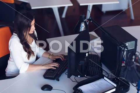 Concentrated middle aged woman working on her computer. Start-up office Stock Photos