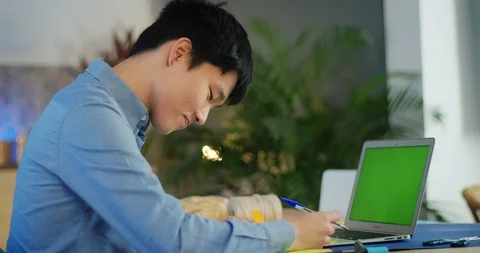 Concentrated millennial guy leaning back on chair looking at laptop green screen Stock Footage 124326122