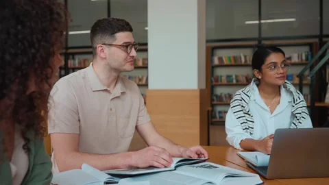 Concentrated multinational students studying and talking in library Stock Footage 250339589