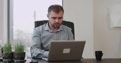 Concentrated office worker sitting on his work place and working on his laptop Stock Footage 100020899