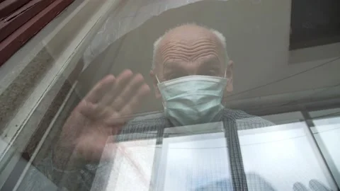 Concentrated old man in face mask holds hands on window Stock Footage 161495744