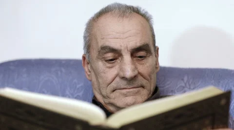 Concentrated old man reading a book on his sofa 스톡 동영상 47826766