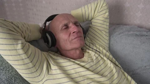 Concentrated older man lying on couch and listening music Video stock 166048628