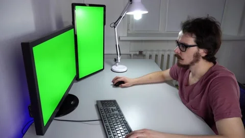 Concentrated programmer is working on computer with chroma key on two monitors Stock Footage 161752276