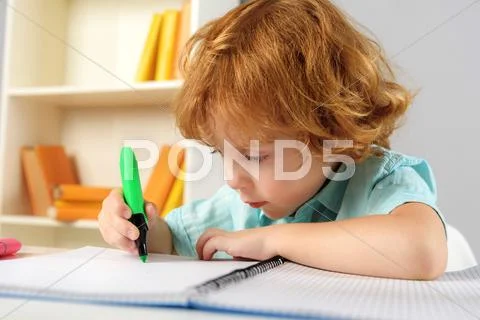 Concentrated pupil sitting with marker Stock Photos