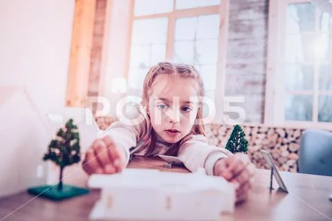 Concentrated schoolgirl congregating toy constructor at cozy home Stock Photos