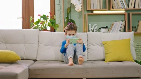 Concentrated small boy using a smartphone to play a game while staying at home Stock Footage 127710838