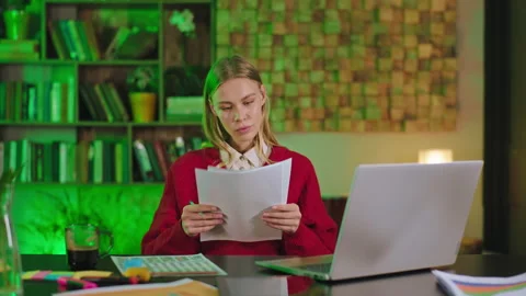 Concentrated student blonde lady doing her college project at home using the Stock Footage 136541096