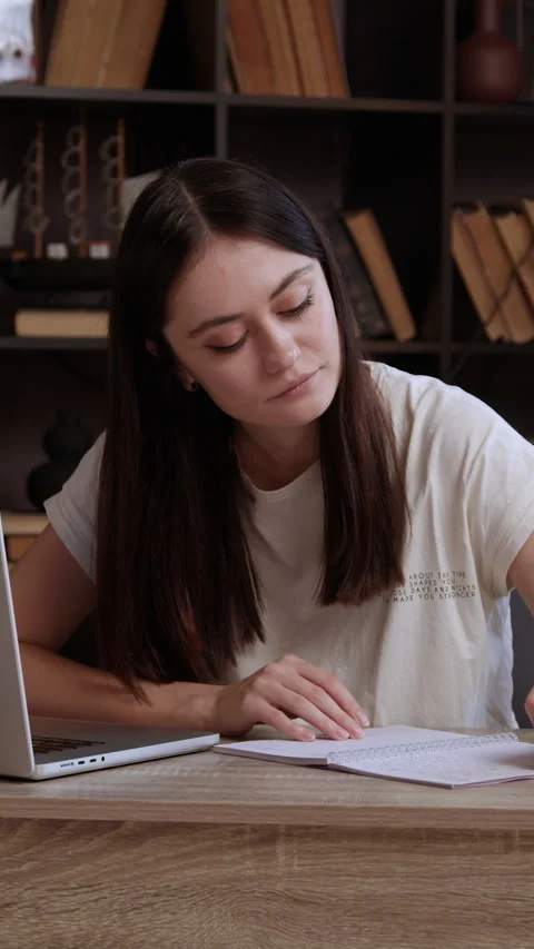 Concentrated student sitting at desk in library, writing essay, making notes in Stock Footage 305407408