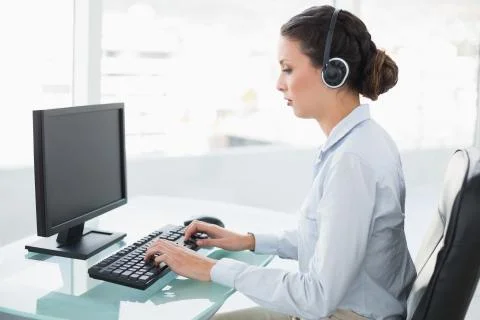 Concentrated stylish brunette operator using a computer Stock Photos