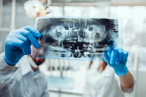 Concentrated two dentists looking at x-ray. focus on x-ray. Stock Photos