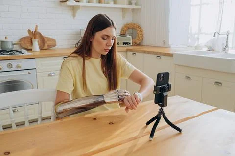 Concentrated woman controls bionic arm using smartwatch Stock Photos