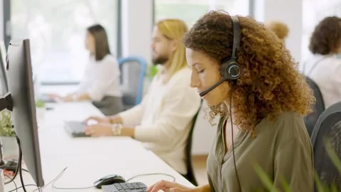 Concentrated woman using computer and headset in a coworking Stock Footage 261422371