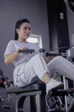 Concentrated woman using row machine in gym for back workout Stock Photos