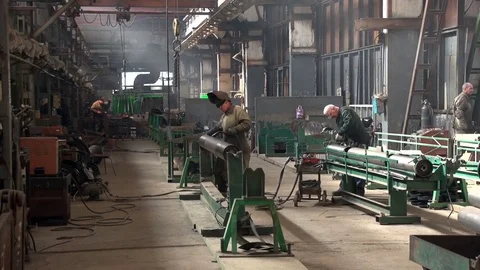 A concentrated worker welds some cylinder metal piece at a spacious plant. 库存影片 82295877