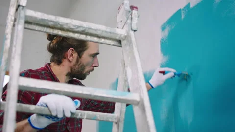 Concentrated working charismatic man using small brush to paint perfect the Stock Footage 171227120