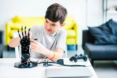 Concentrated young boy constructing his robotic hand at home Stock Photos