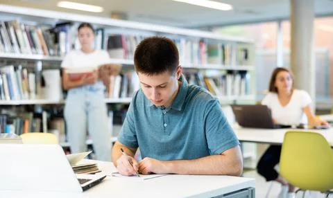 Concentrated young man checking plans in calendar while studying in the library 스톡 사진