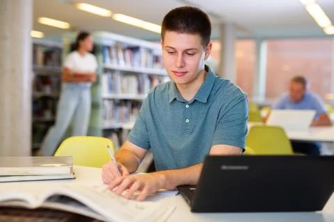 Concentrated young man checking plans in calendar while studying in the library Foto stock