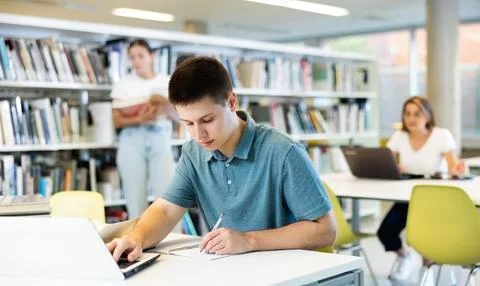 Concentrated young man checking plans in calendar while studying in the library Foto stock
