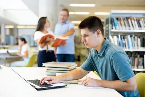 Concentrated young man checking plans in calendar while studying in the library 스톡 사진
