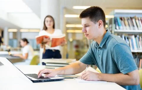 Concentrated young man checking plans in calendar while studying in the library 写真素材