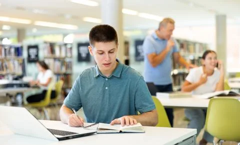 Concentrated young man checking plans in calendar while studying in the library 스톡 사진