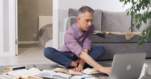 Concentrated young man looking for information in many books and textbooks and Stock Footage 149674974