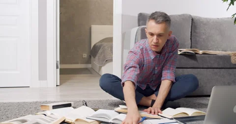 Concentrated young man looking for information in many books and textbooks and Stock Footage 150703936
