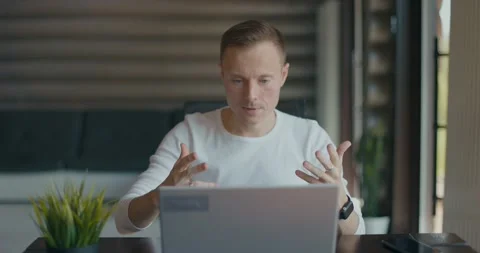 Concentrated young man makes video call on laptop while sitting in room at his Video stock 197816051