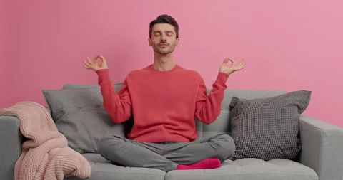 Concentrated young man meditates or practices yoga sits crossed legs breathes Stock Footage 143625515