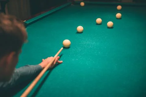 Concentrated young man playing. He hold billiard cue and aiming to break ball on Stockfoto's