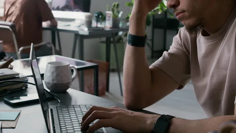 Concentrated Young Man Rubbing Forehead and Typing on Laptop in Office Stock Footage 299205461