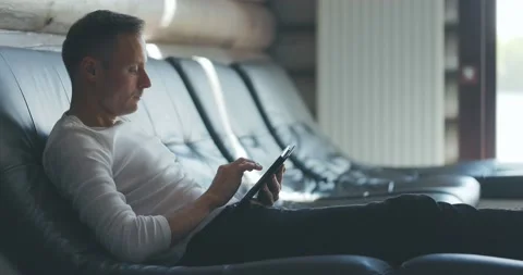 Concentrated young man is sitting on sofa in room, looking for information on Stock Footage 197572385