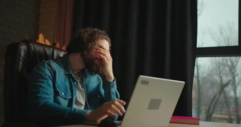 Concentrated young man working on a laptop computer while sitting on a black Stock Footage 246748363