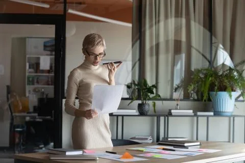 Concentrated young manager using virtual assistant on phone. 写真素材