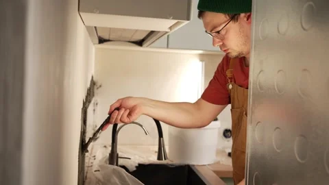 Concentrated young worker in overalls using a spatula to apply putty to the Stock Footage 344564789