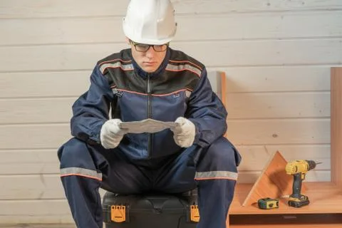 Concentrated young worker reading the instructions to assemble furniture. Stock Photos