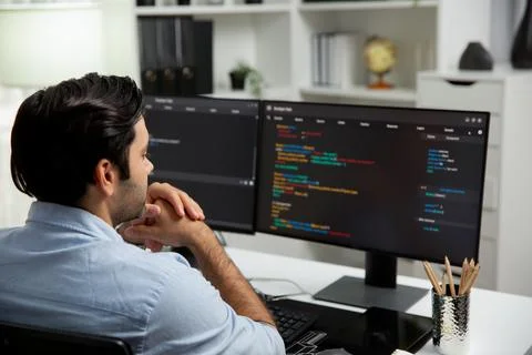 Concentrating in smart IT developer working coding on two pc screen. Surmise. Stock Photos