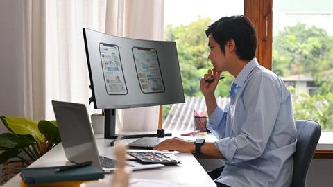 Concentred asian man developer working on mobile application software design Stock Photos