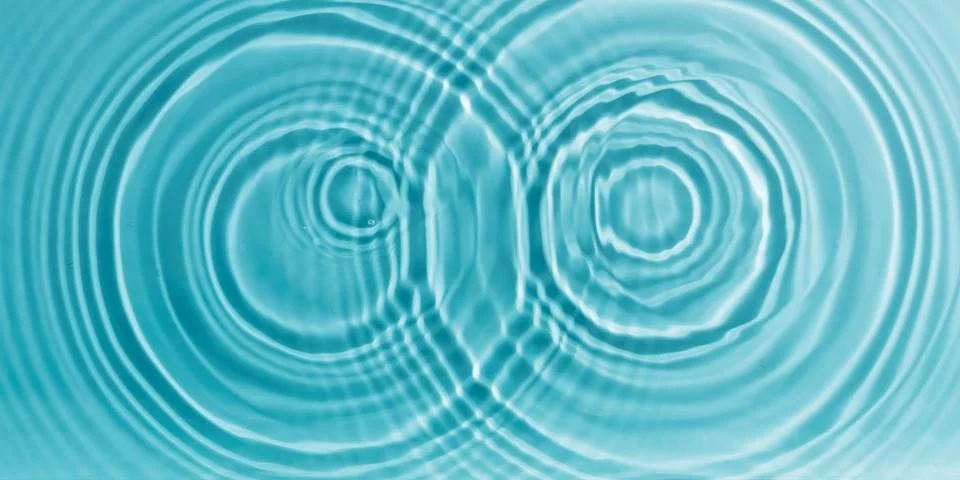Concentric water waves interference pattern on turquoise fluid surface Stockfoto's