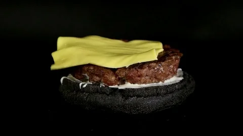 Concept of adding the ingredients to black Cheese Burger Stock Footage 77585910
