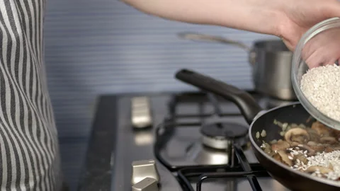Concept of adding risotto rice into a pan on a gas stove in 4K. Stock Footage 134693817