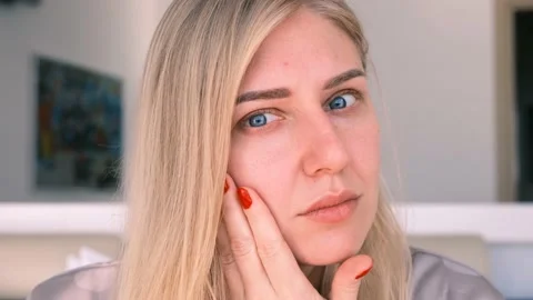 Concept of aging. Young attractive blue-eyed blonde woman looks into camera, as Stock-Footage 165702779