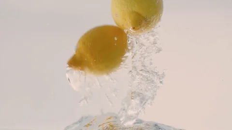 Concept Background: Lemons Slowly Fall Into The Water Stock Footage 97608900