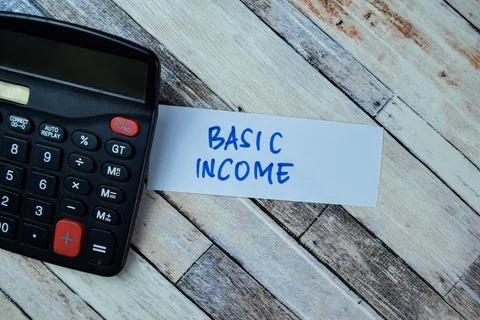 Concept of Basic Income write on sticky notes isolated on Wooden Table. Stock Photos
